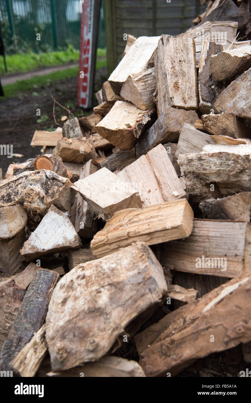 Signer la vente de sciage pour les feux et woodburners près d'un grand tas de bois séché et haché mélangé de sciage Banque D'Images