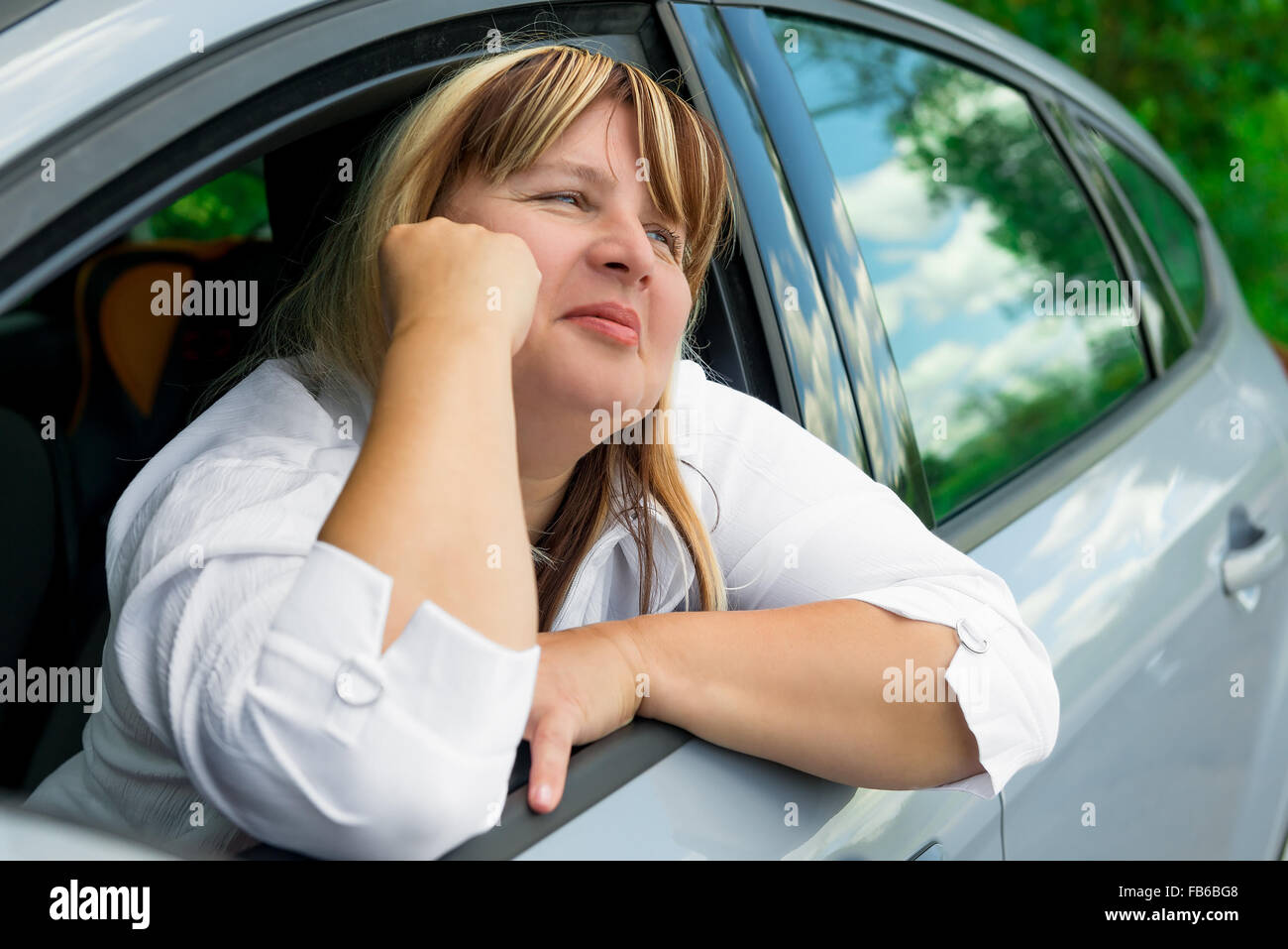 Femme mature dans une voiture gris se reposant Banque D'Images