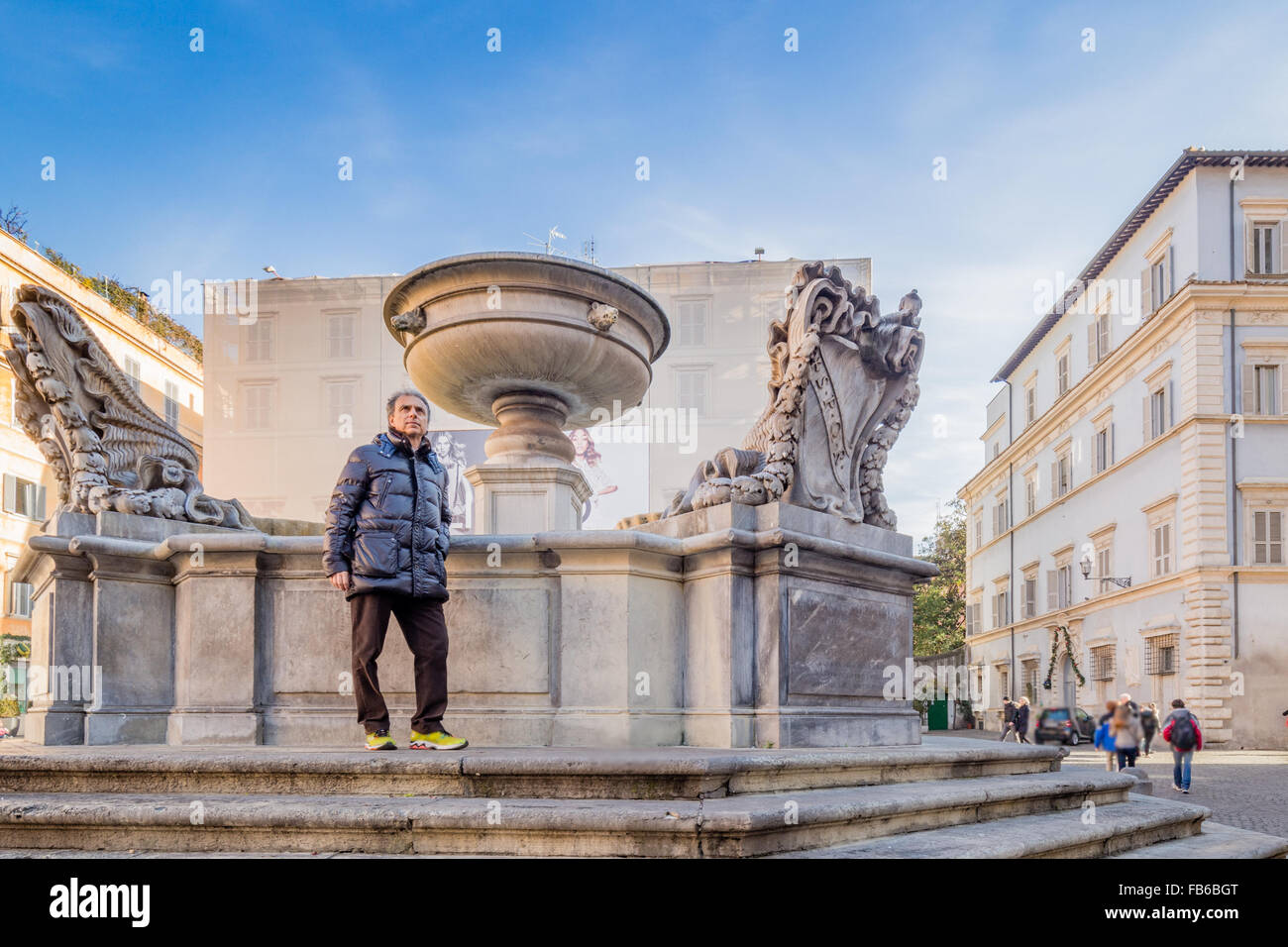 Homme de race blanche d'âge moyen aux cheveux gris vêtus de noir veste vers le bas près de l'ancienne fontaine romaine à Rome Banque D'Images