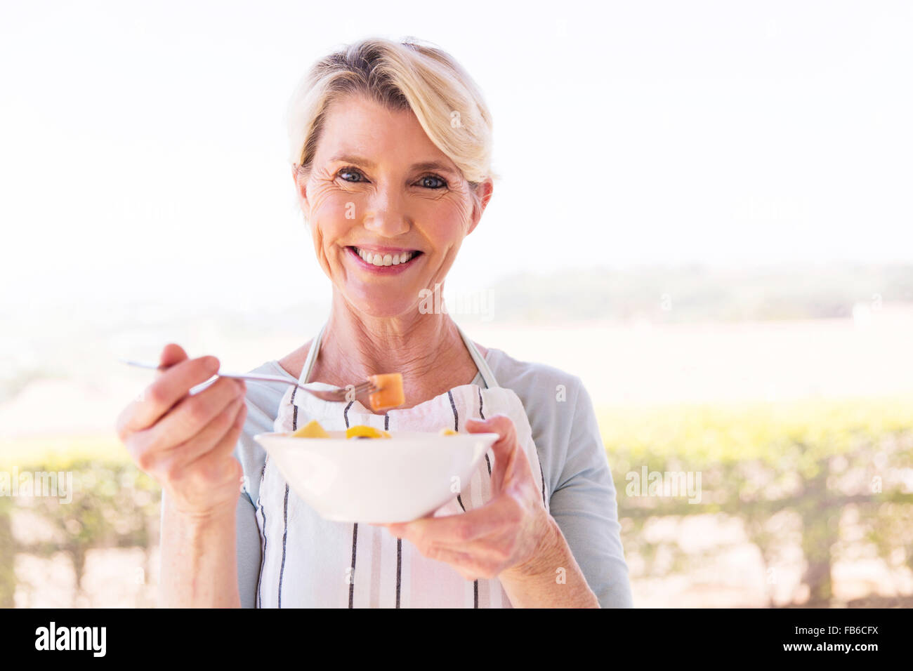 Happy young woman eating salad at home Banque D'Images