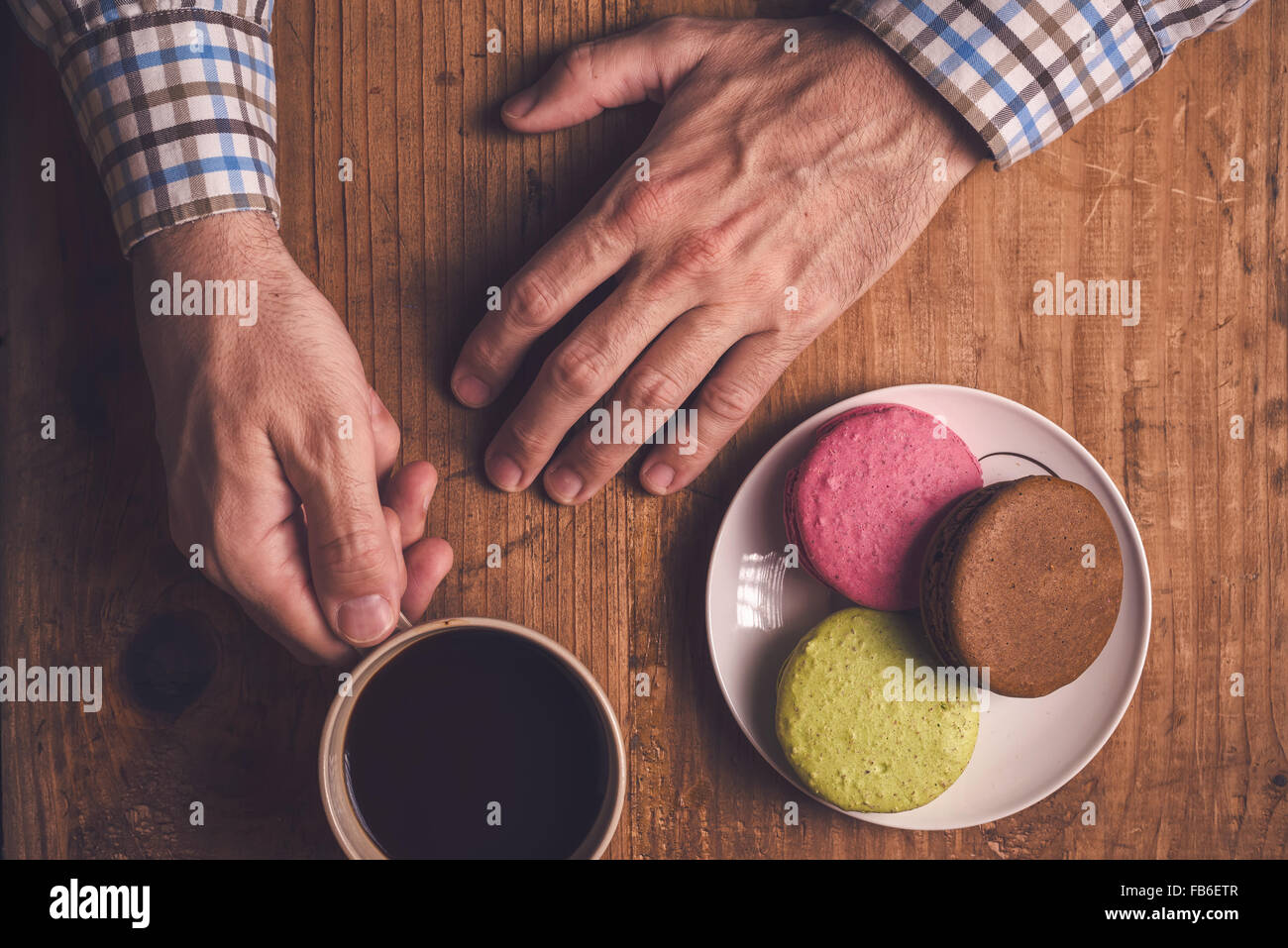 Café et biscuits macaron sur table, male hands holding cup avec boisson chaude, vue d'en haut, aux couleurs rétro Banque D'Images