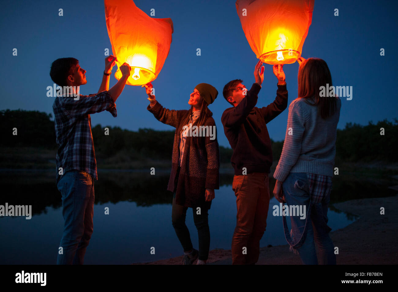 Les randonneurs, hommes et femmes la libération des lanternes en papier au Lakeshore Banque D'Images