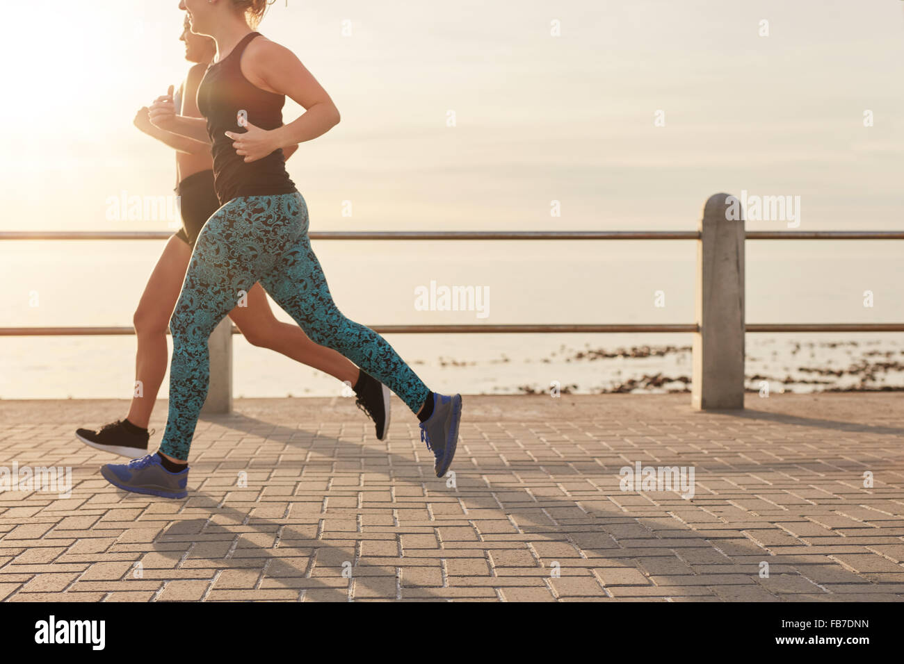 Cropped shot de deux jeunes femmes en marche le long d'une promenade en bord de mer. De jeunes coureurs travaillant ensemble sur une route par le s Banque D'Images