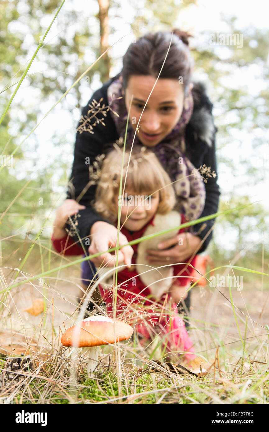 Mère montrant champignon à fille sur terrain Banque D'Images