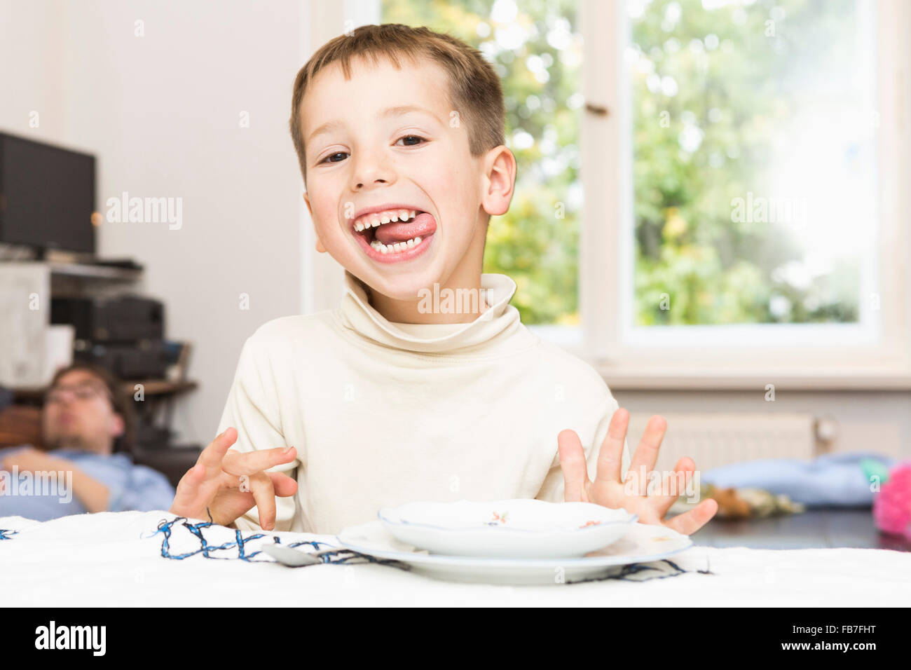 Portrait of cute boy sticking out tongue at table Banque D'Images