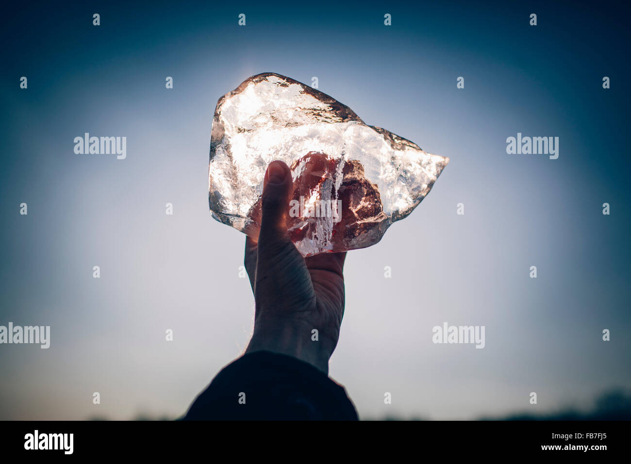 Cropped hand of man holding ice contre le ciel au crépuscule Banque D'Images