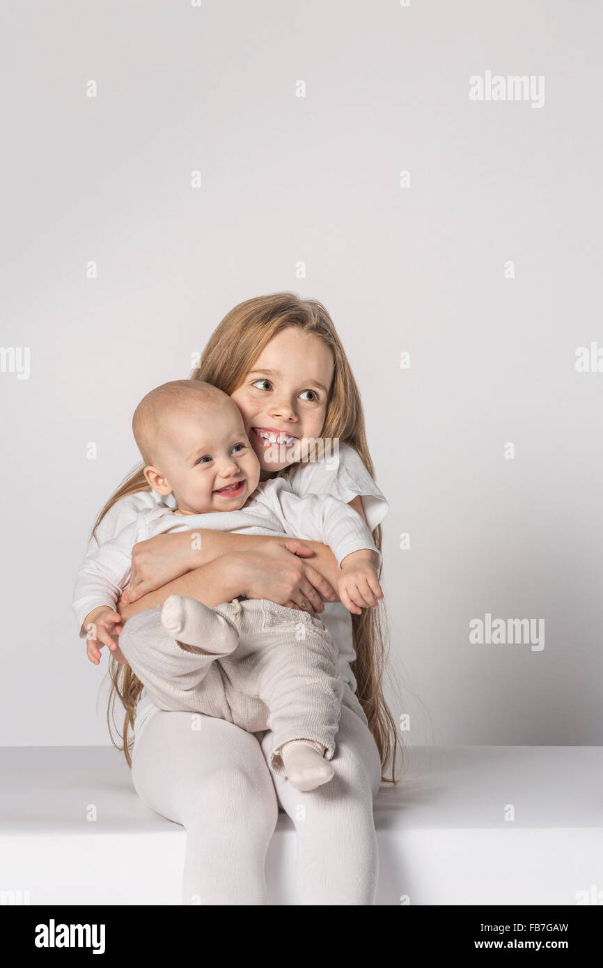 Cheerful baby girl sitting avec sœur against white background Banque D'Images