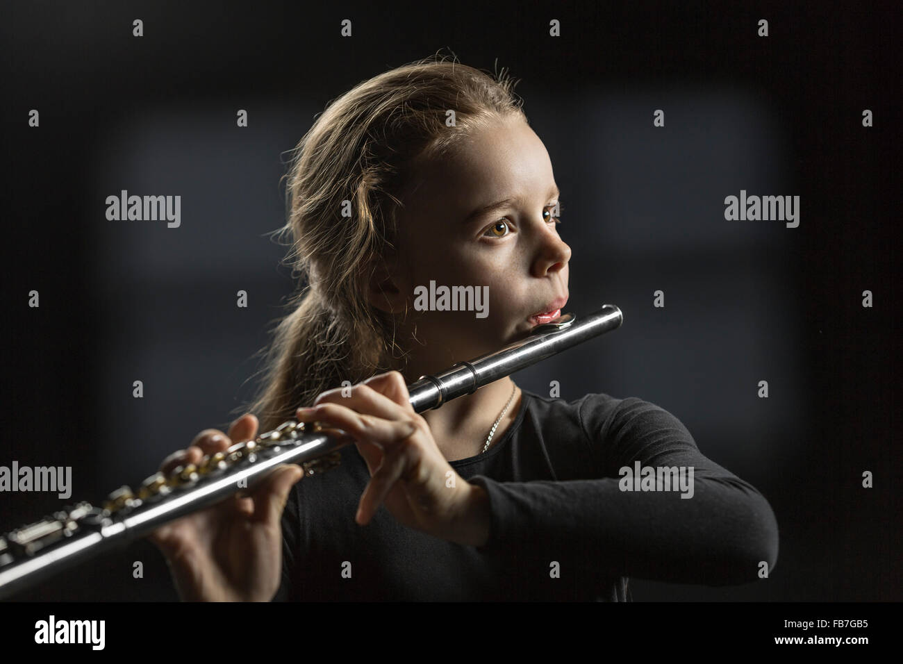 Girl playing flute sur fond noir Banque D'Images