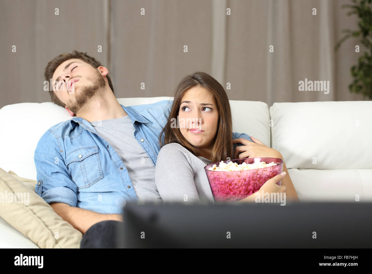 Quelques problèmes d'incompatibilité de regarder la télévision assis sur un canapé à la maison Banque D'Images