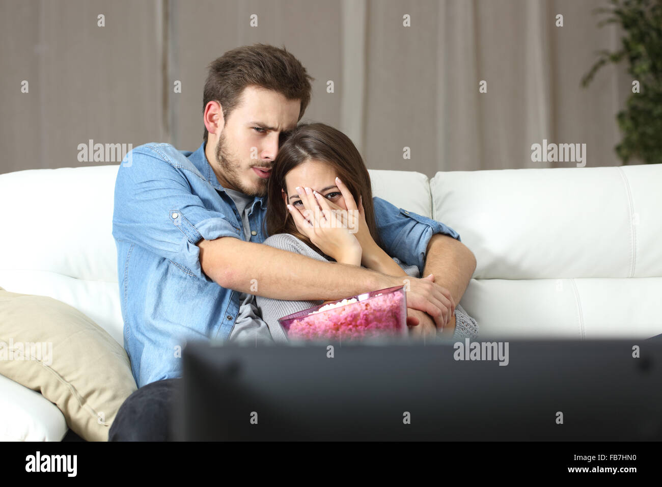Couple et profiter de la terreur tv film assis sur un canapé à la maison Banque D'Images