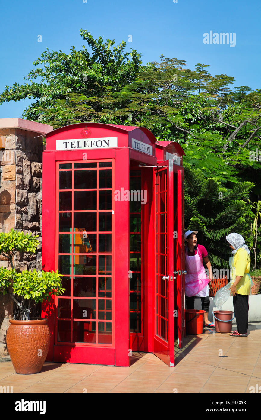 Femmes ayant une conversation sur le côté d'une boîte téléphonique rouge désaffectée à Kota Kinabalu, Sabah, Malaisie. Banque D'Images