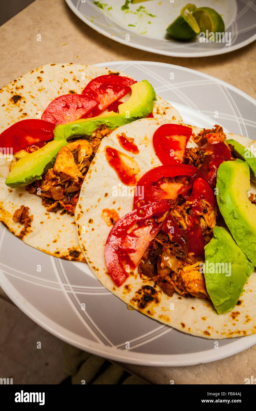 Un poulet taco Tortilla de farine avec de l'avocat, tomate et sauce taco sur une plaque Banque D'Images