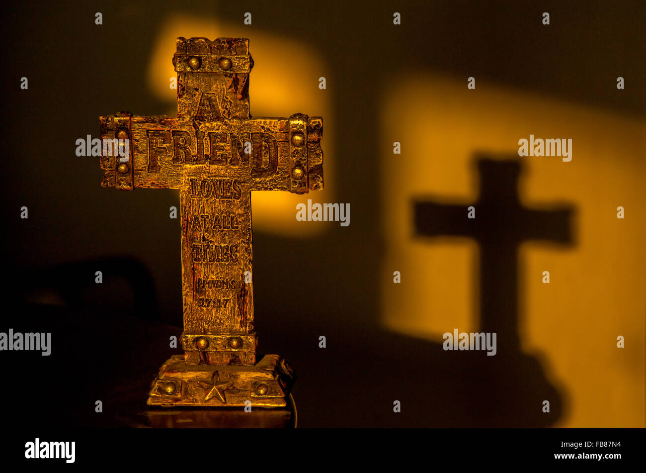Croix chrétienne au début de la lumière du soleil du matin, jette une ombre sur le mur. Banque D'Images