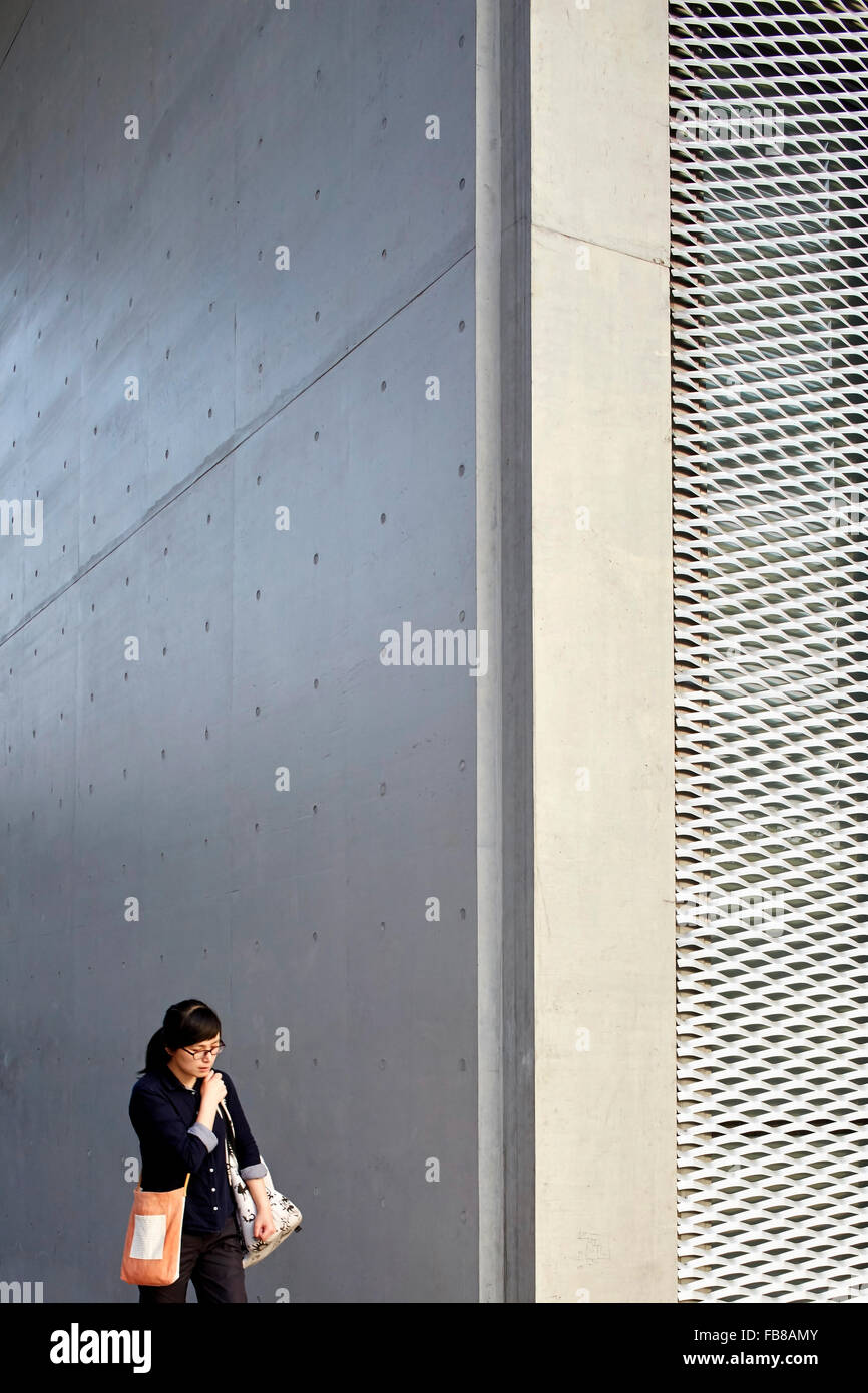 Femme à côté de façade en béton. Long Museum West Bund, Shanghai, Chine. Architecte : Atelier Deshaus, 2015. Banque D'Images
