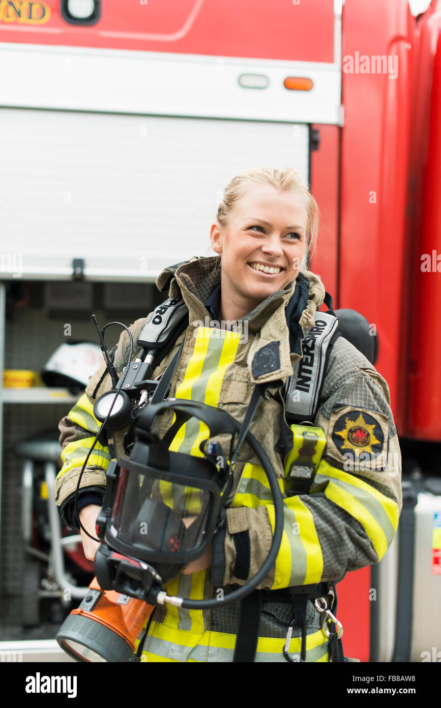 La Suède, Smiley pompier femelle debout à côté d'un camion de pompiers Banque D'Images