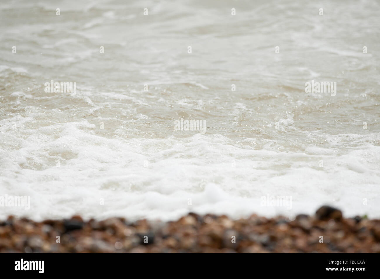 Les vagues de la mer mousseuse lave et règne sur galets sur le littoral de la plage de galets Banque D'Images