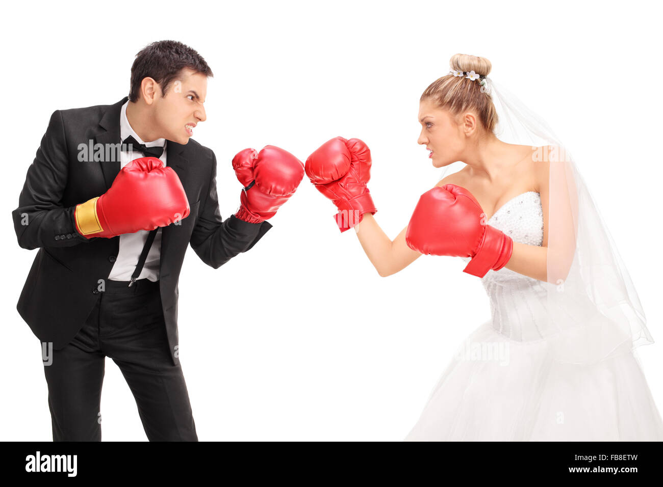 Les jeunes époux et une épouse se battre avec des gants de boxe isolé sur fond blanc Banque D'Images