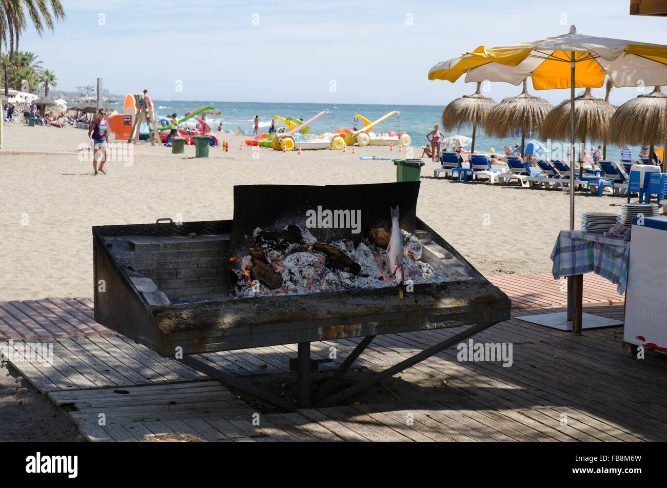 Lignes d'anchois et de sardines sur des brochettes en bois cuisson sur un barbecue sur la plage Playa de la Vénus à Marbella Banque D'Images
