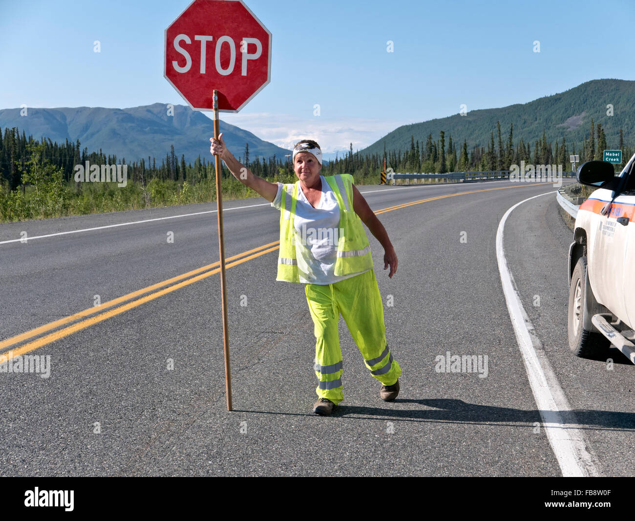 Le contrôle de la circulation, la sécurité des femmes portant des couleurs, affichage, panneau 'Stop' autoroute Alcan. Banque D'Images