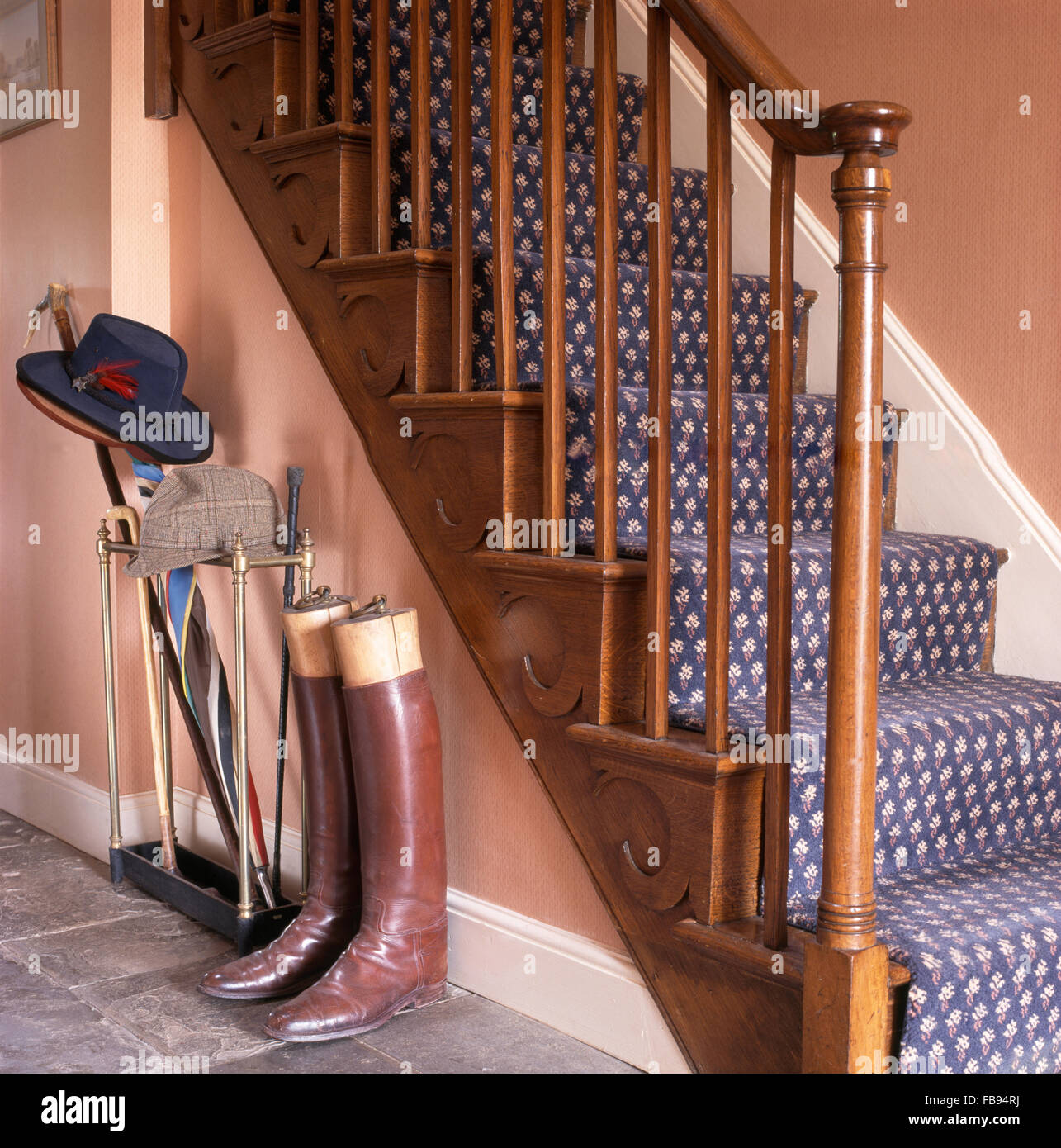 Bottes d'équitation en cuir au pied de l'escalier avec tapis à motifs bleu Banque D'Images