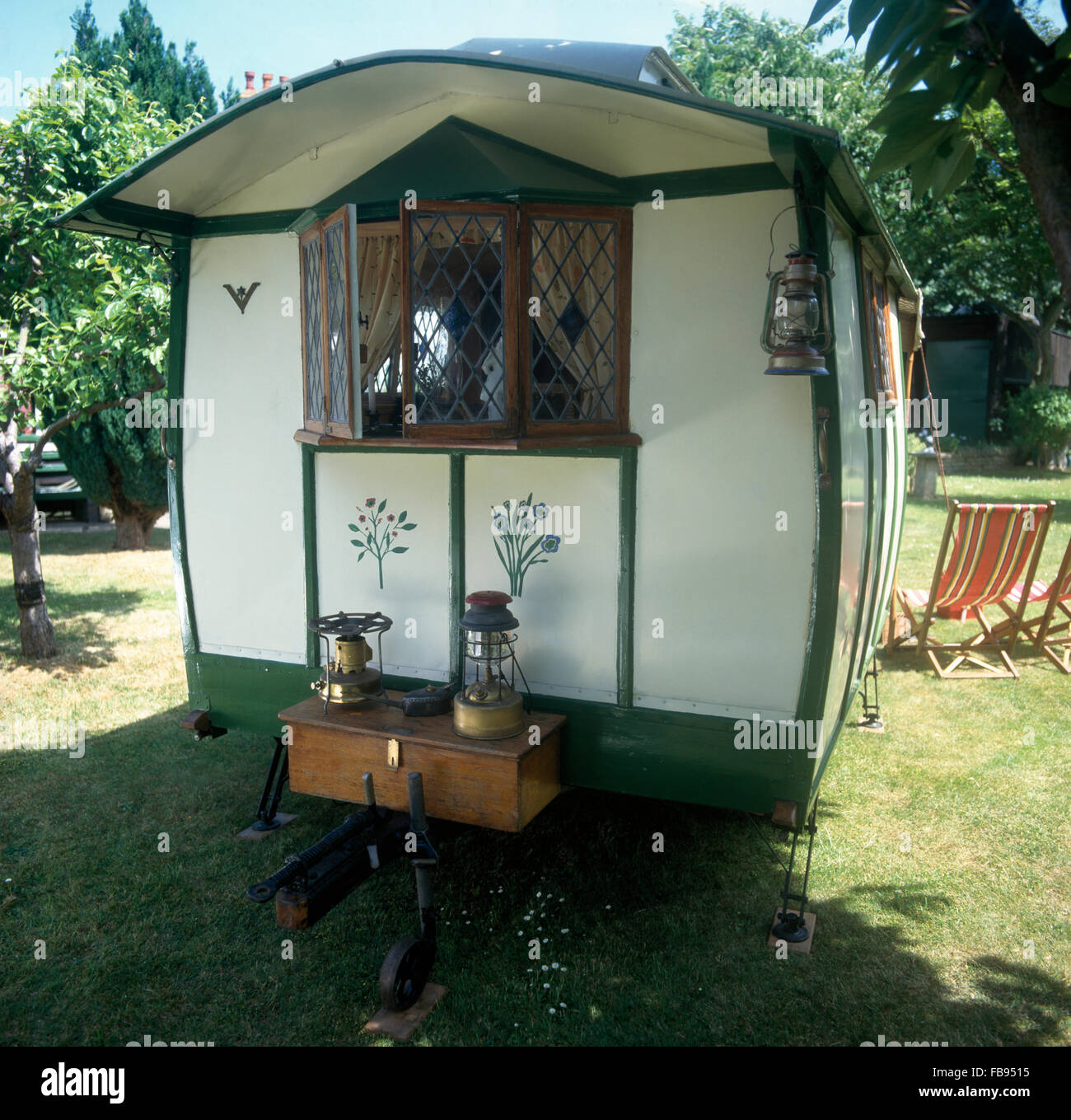 De l'extérieur d'un cream 50 caravane avec une petite fenêtre en treillis au-dessus d'une boîte en bois avec une cuisinière primus Banque D'Images