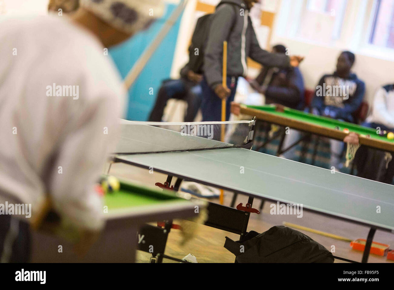 Les jeunes hommes non identifiables, jouer au ping-pong et piscine dans un centre communautaire du Royaume-Uni Banque D'Images