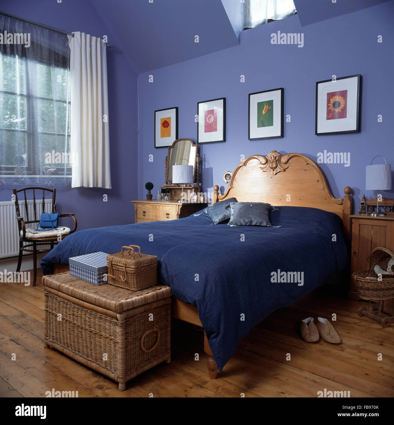 Wicker poitrine à la nourriture d'un pin lit avec une couette bleu mauve dans une chambre à coucher des années 90 Banque D'Images