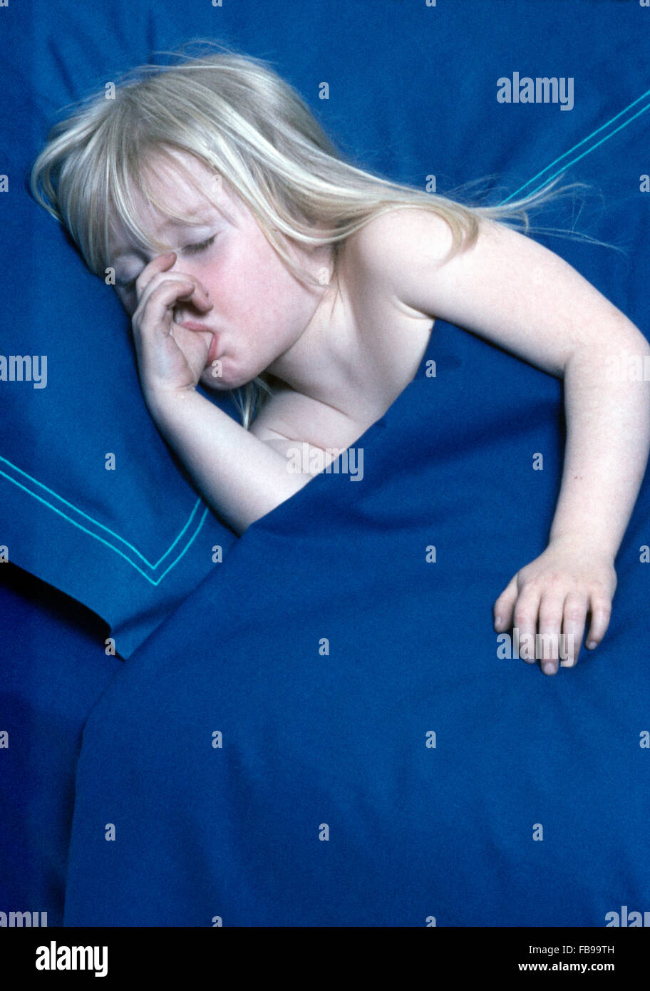 Petite fille blonde de sucer son pouce et dormir dans le lit avec couette  et oreillers bleu Photo Stock - Alamy