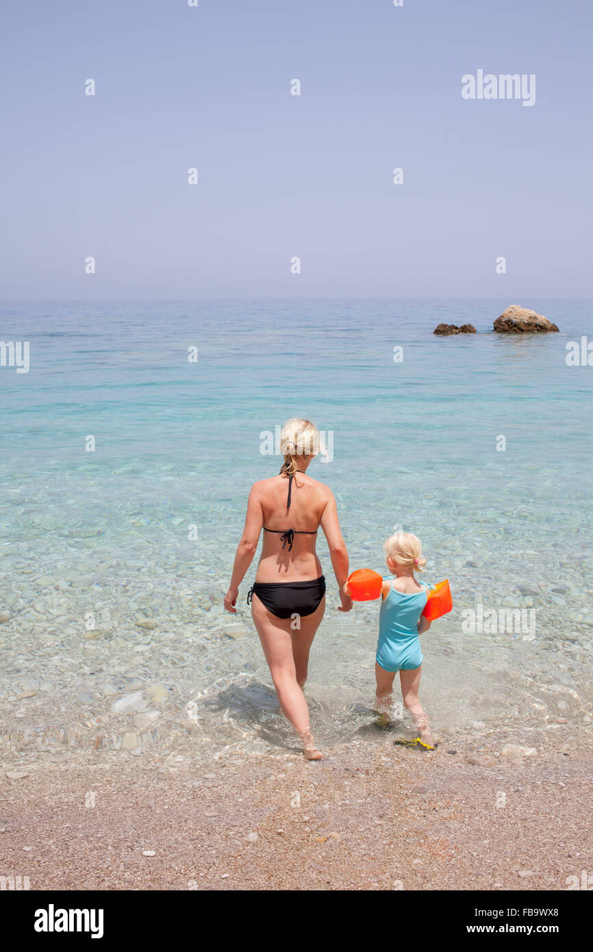 Grèce, Karpathos, Amopi, Woman and girl (6-7) walking in sea Banque D'Images