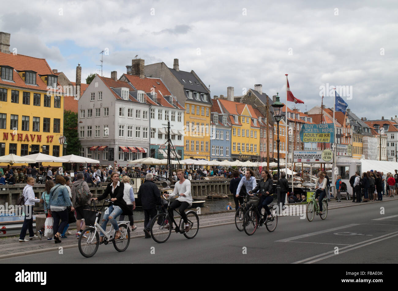 Les cyclistes passant les maisons colorées contenant des bars et restaurants de la canal au nouveau port de Nyhavn Copenhague Danemark Banque D'Images