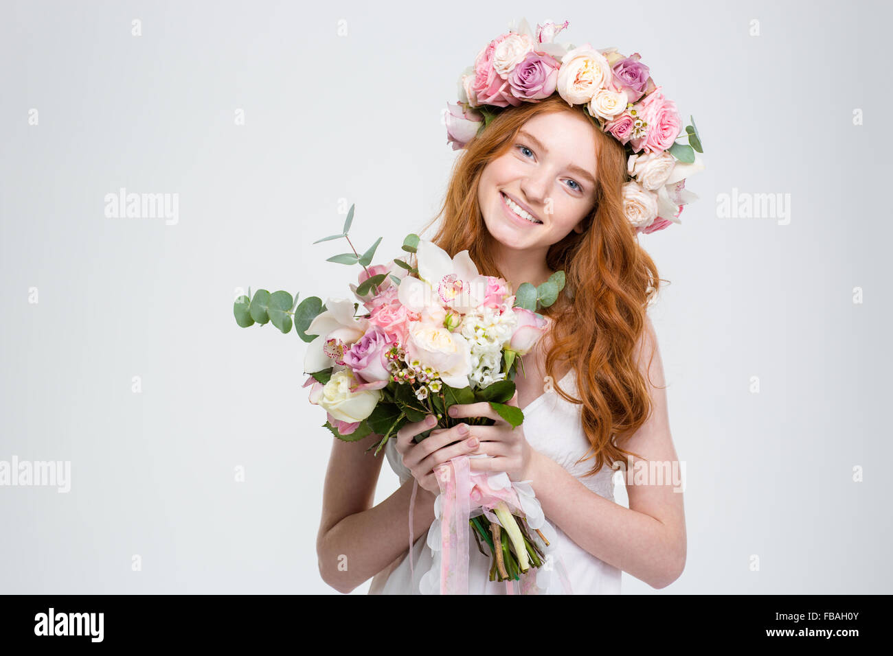 Smiling attractive young woman avec longs cheveux rouges en gerbe holding bouquet de fleurs sur fond blanc Banque D'Images
