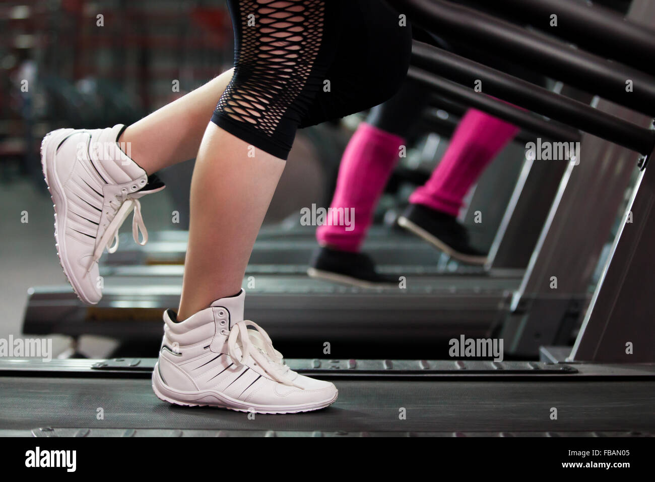 Close-up of women legs dans sneakers sur tapis roulant dans une salle de sport Banque D'Images
