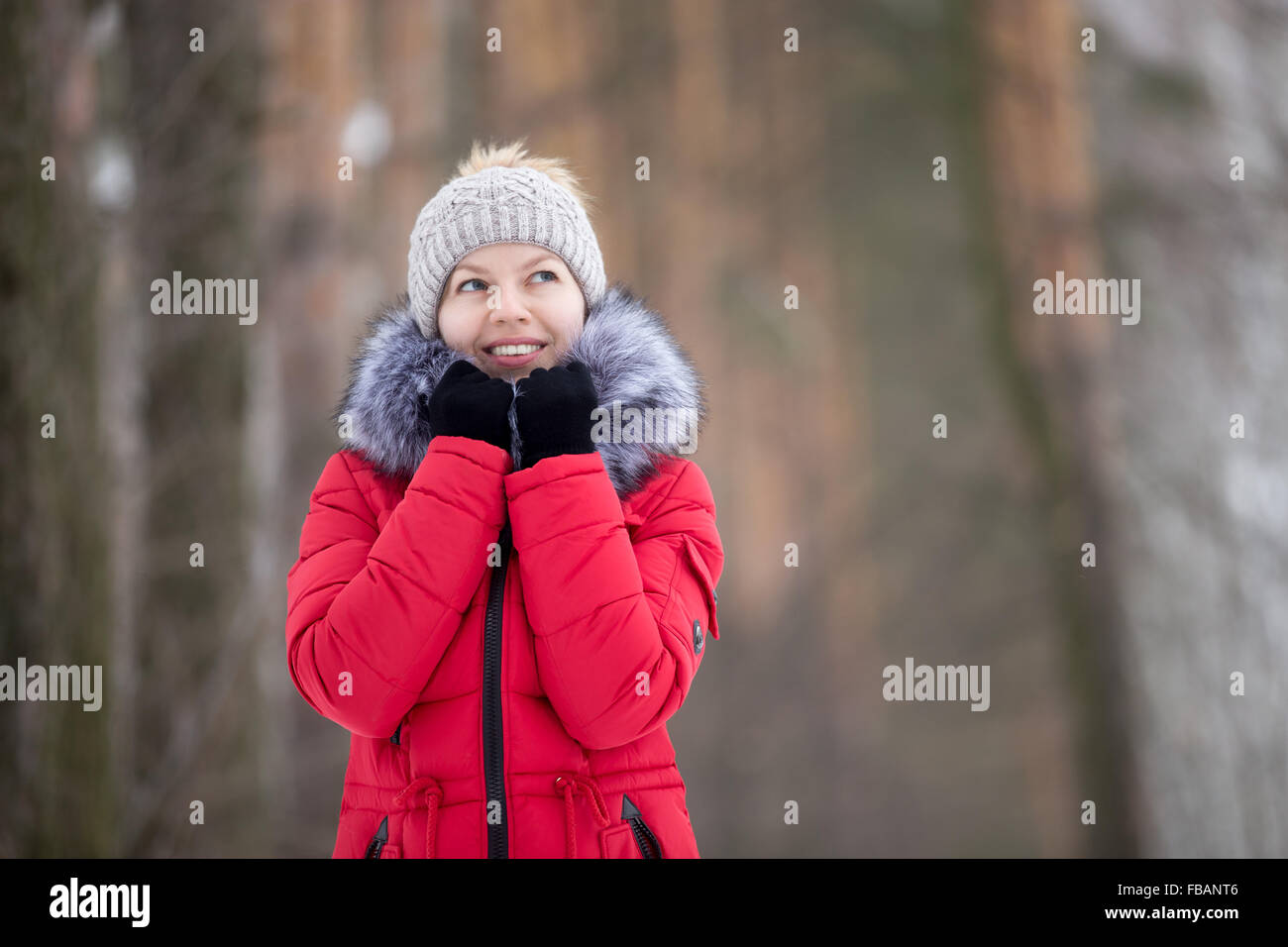 Belle fille de sourire et chapeau tricoté manteau d'hiver rouge rétractable elle-même jusqu'au col de fourrure, à l'extérieur Banque D'Images