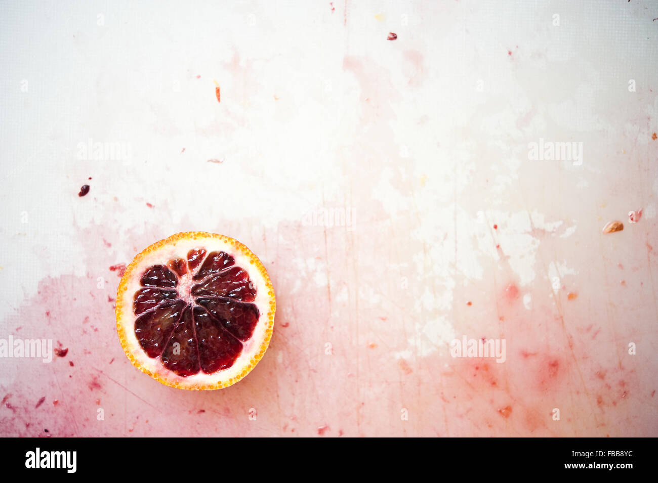 Seule la tranche d'orange sanguine sur une planche à découper colorée avec du jus Banque D'Images