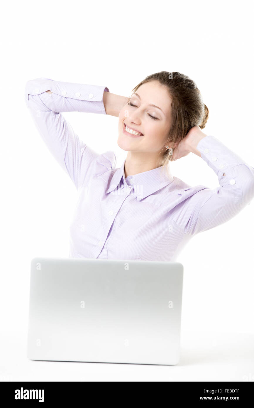 Happy smiling belle fille de bureau prenant une pause s'étend en face d'un ordinateur portable avec expression rêveuse, relaxant avec ey fermé Banque D'Images