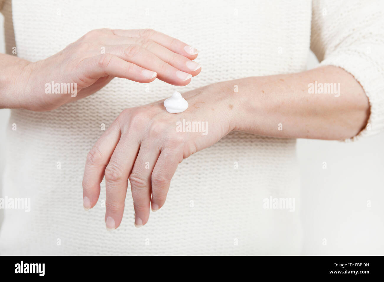 Les mains d'une femme âgée avec crème main Banque D'Images