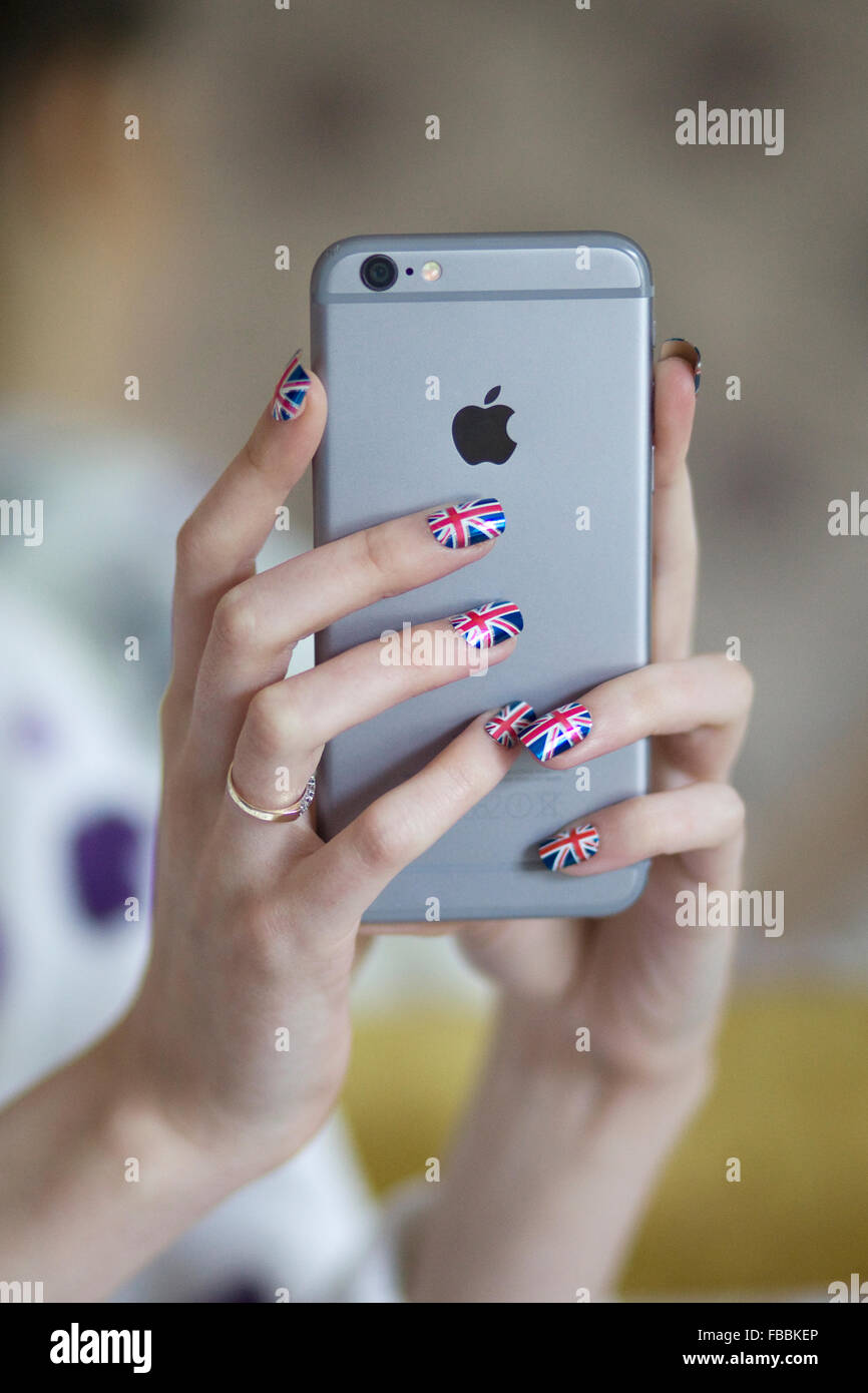 Mains tenant un Apple i phone avec ongles peints dans l'Union jack Banque D'Images