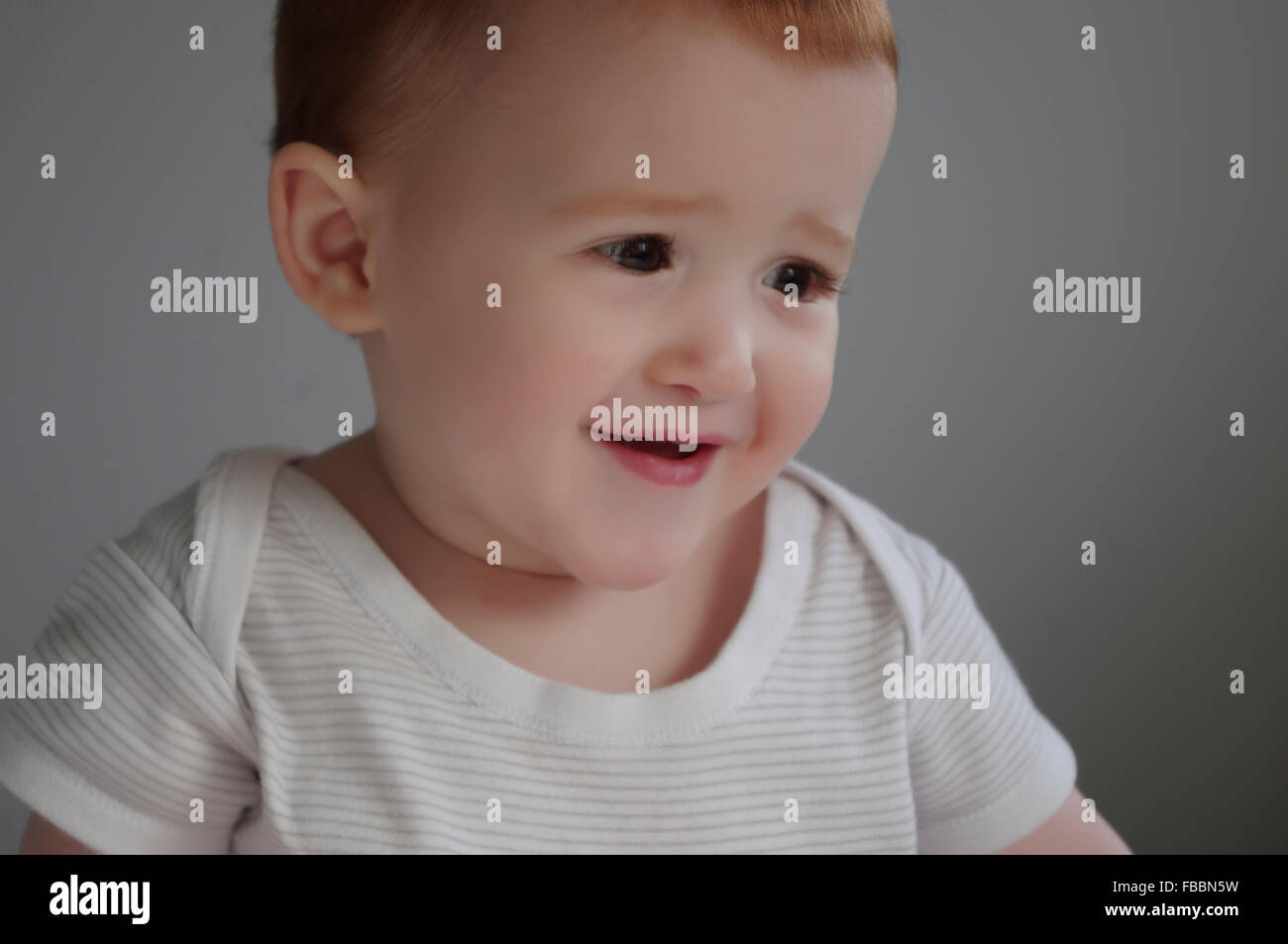 Portrait of a cute red haired Caucasian baby girl un gilet blanc à rayures Banque D'Images