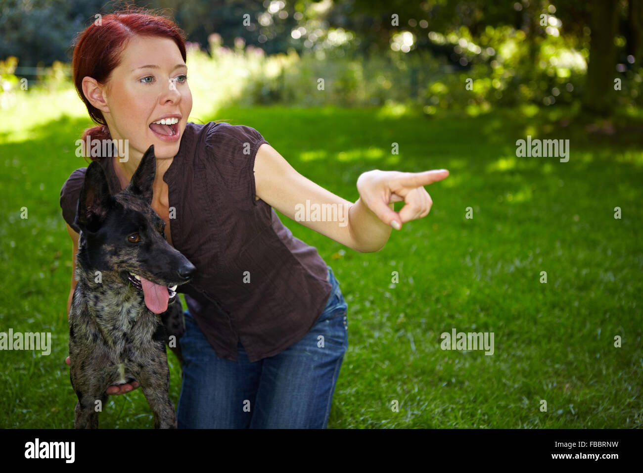 Femme avec un chien dans un parc indiquant avec son index Banque D'Images