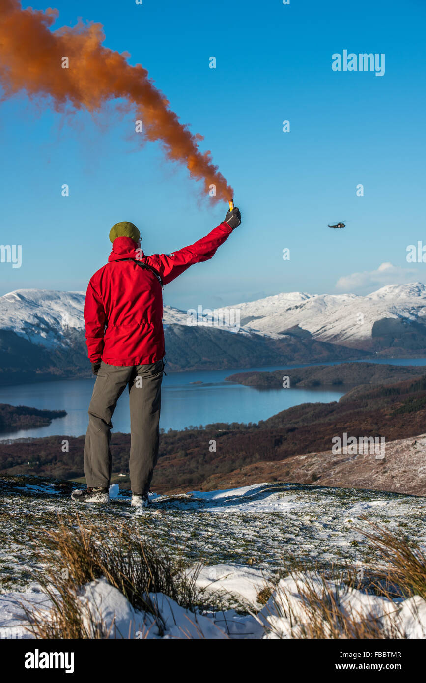 Membre de l'équipe de secours en montagne avec une torche de fumée pour attirer helicopter Banque D'Images