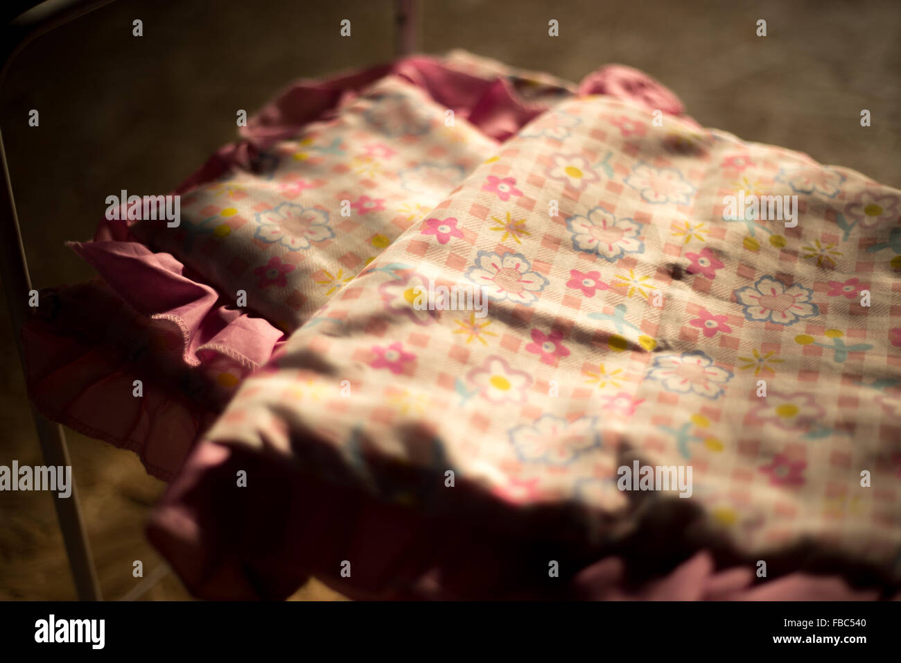 Jouet lit dans la lumière du matin avec oreiller et housse de couette avec fleur rose ornement, close-up Banque D'Images