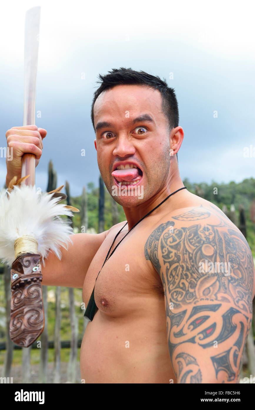 Mâle maori reproduisant une partie du défi maori (Haka) avec une lance au village maori de te Puia, Rotorua, Île du Nord, Nouvelle-Zélande Banque D'Images