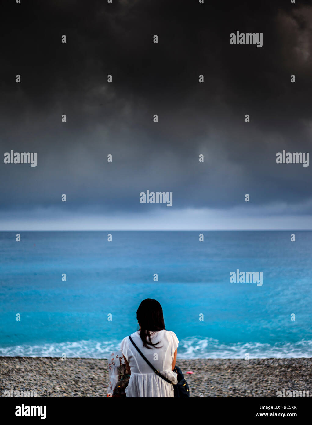 Femme assise sur la plage de Nice France Banque D'Images