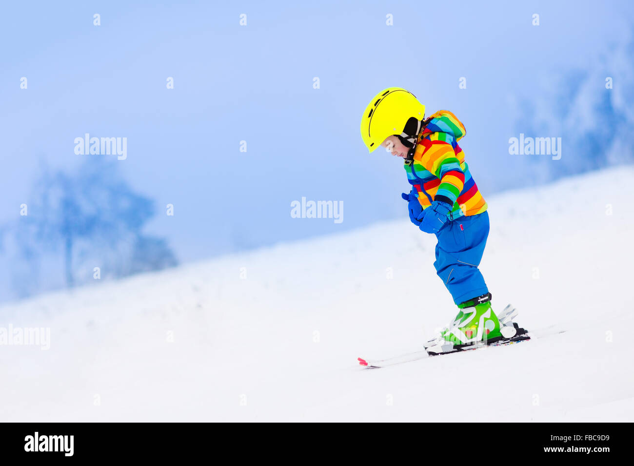 Enfant de ski dans les montagnes. Tout-petit enfant en costume coloré et casque de sécurité l'apprentissage du ski. Sport d'hiver pour la famille Banque D'Images