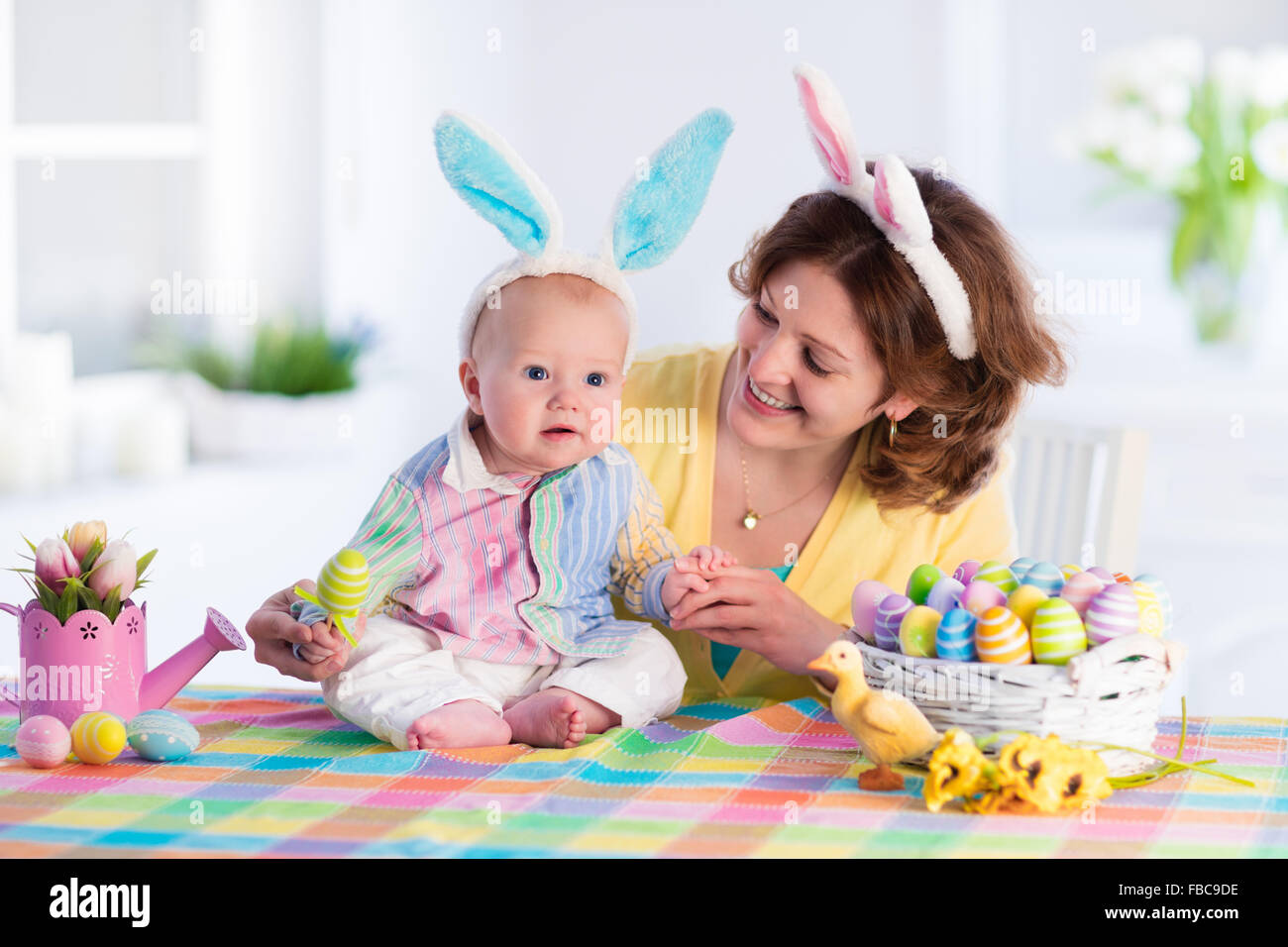 La mère et l'enfant les oeufs colorés de peinture. Maman et bébé avec oreilles de lapin peindre et décorer des oeufs de Pâques. Parent et enfant jouer à l'intérieur Banque D'Images