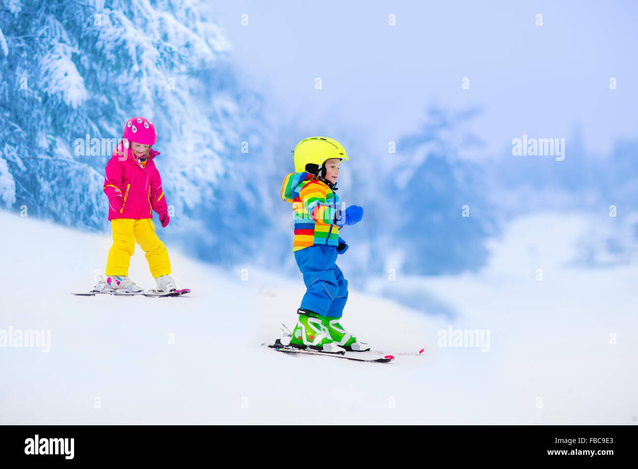 Les enfants de ski dans les montagnes. Tout-petits enfants en costume coloré et casque de sécurité l'apprentissage du ski. Sport d'hiver pour la famille Banque D'Images