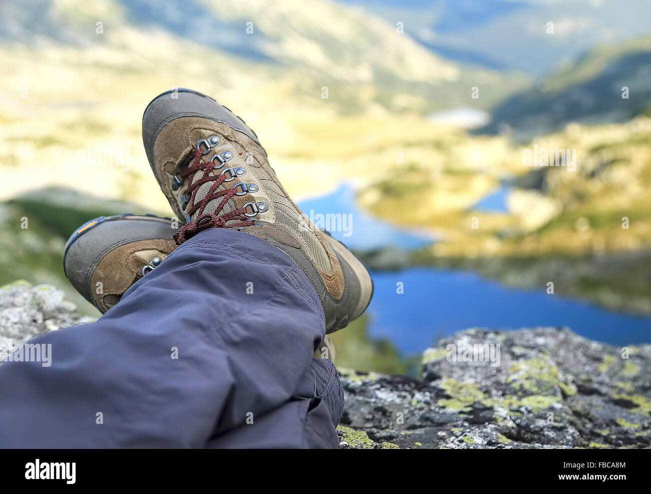 Bottes femme Hiker Resting sur sommet de montagne avec des lacs de montagne dans l'arrière-plan Banque D'Images