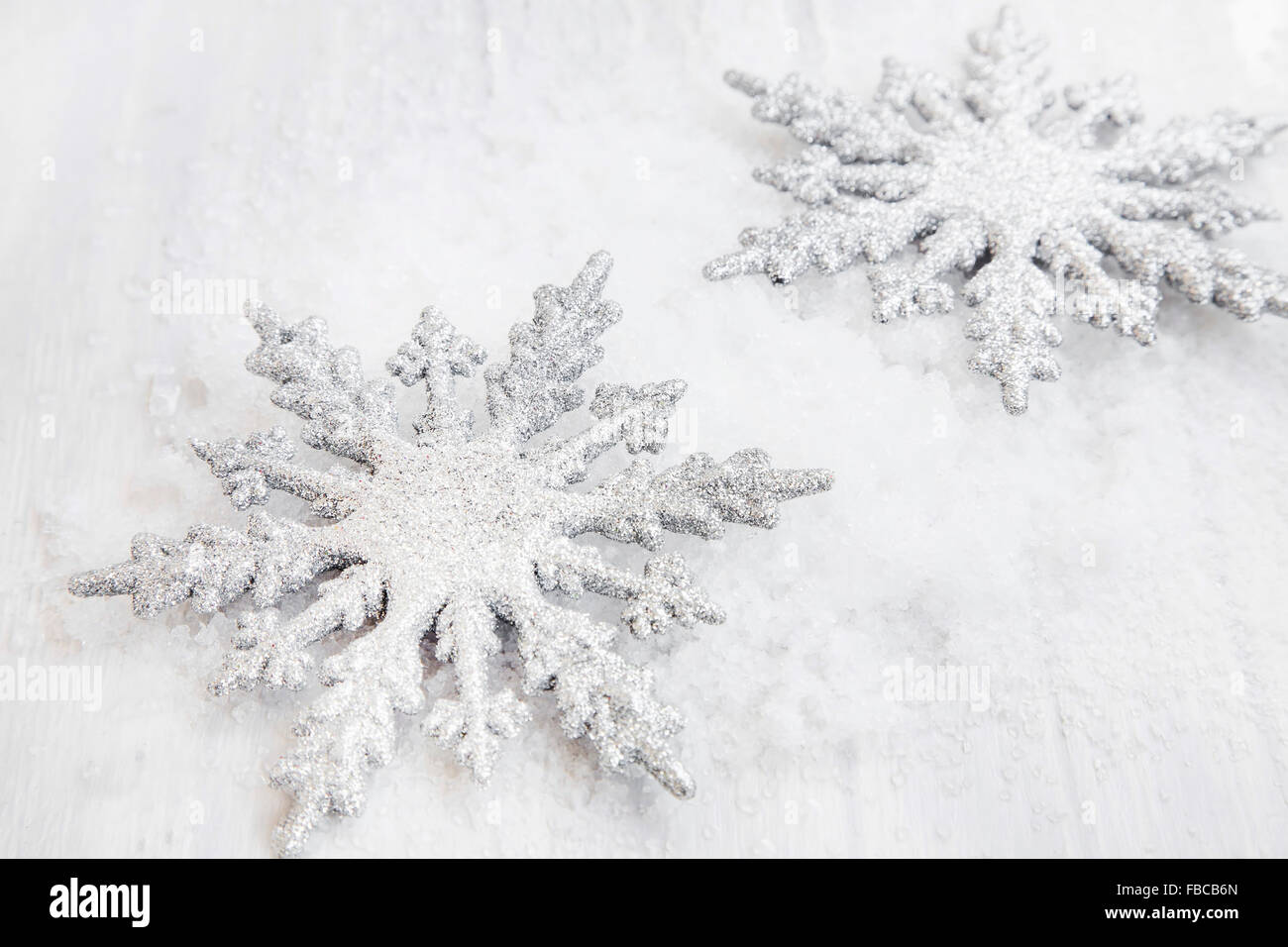 Deux d'argent scintillait Flocons de Noël ornements dans la neige Banque D'Images