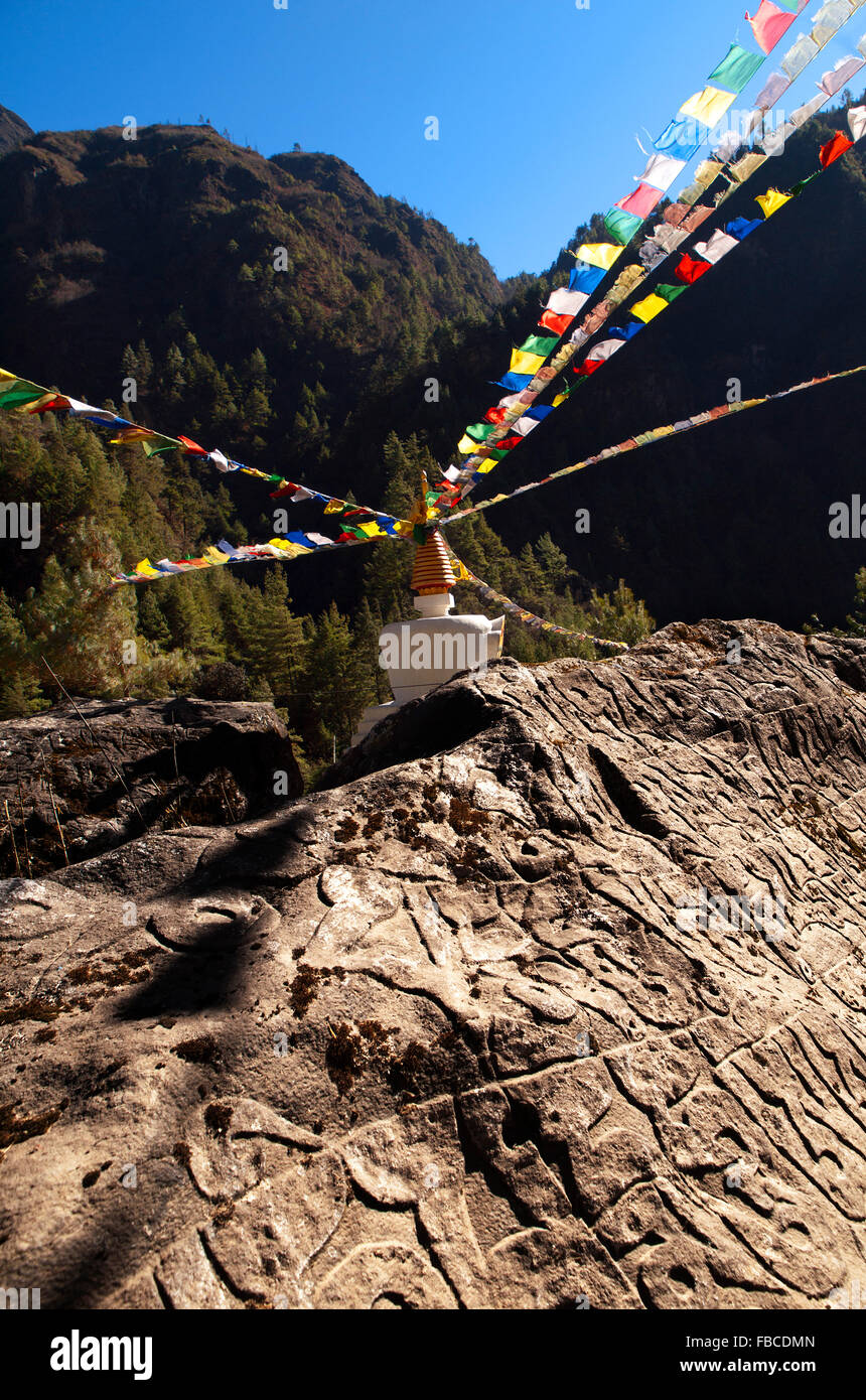 Rocher sculpté bouddhique et les drapeaux de prières, vallée du Khumbu au Népal Banque D'Images Rocher sculpté bouddhique et les drapeaux de prières, vallée du Khumbu au Népal Banque D'Images