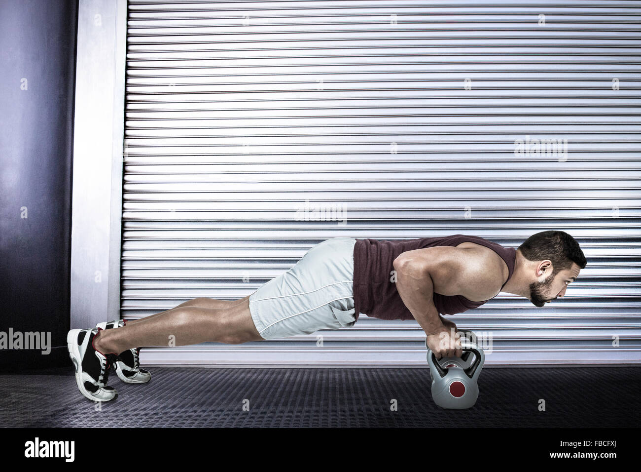 Image composite de l'homme musclé faisant pousser ups avec kettlebells Banque D'Images